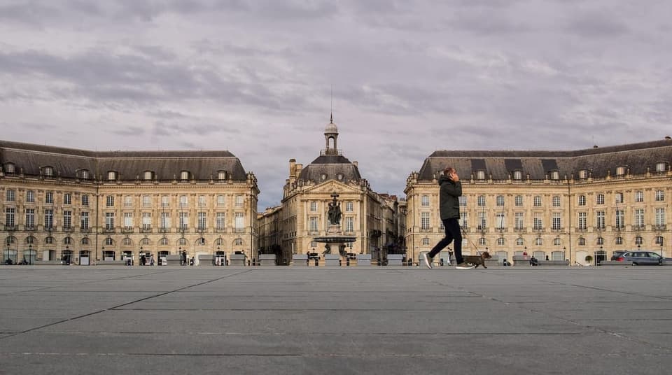 Someone walking a dog across a large city square